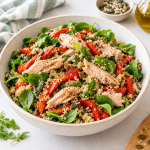 Bol de ensalada templada de quinoa con tiras de pimientos rojos asados, ventresca de bonito y canónigos